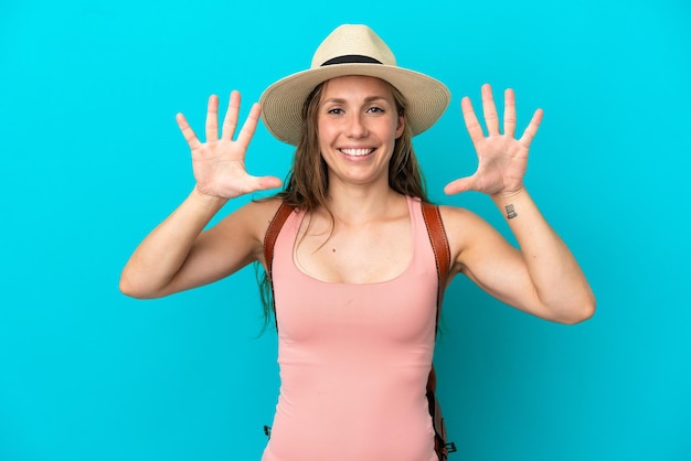 Jeune femme de race blanche en vacances d'été isolée sur fond bleu comptant dix avec les doigts