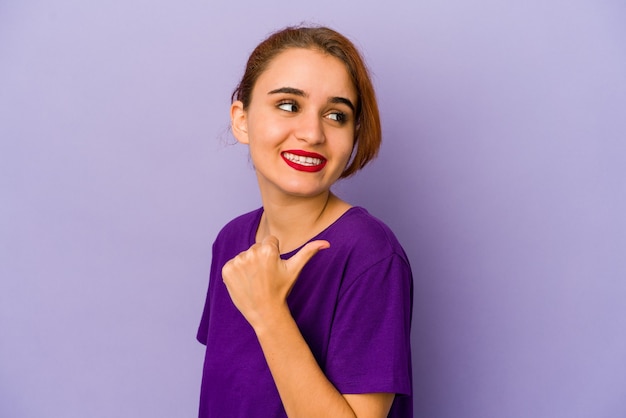 Jeune femme de race mixte arabe pointe avec le pouce, riant et insouciant.