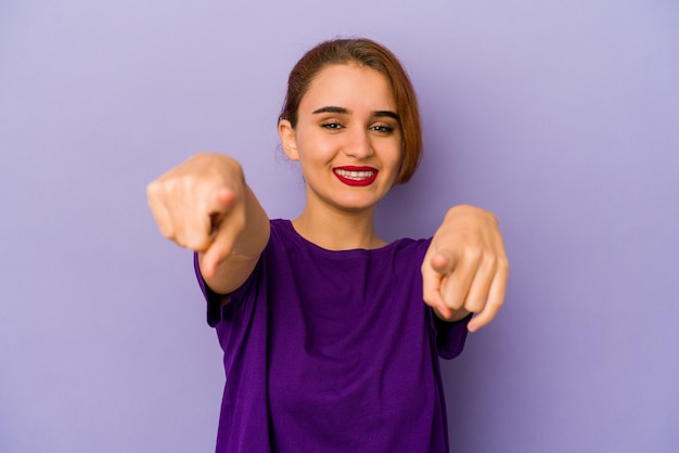 Jeune femme de race mixte arabe sourit joyeux pointant vers l'avant.