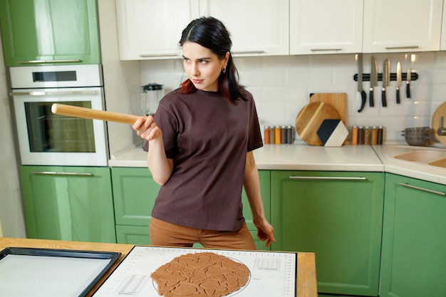 Jeune femme de race mixte brune joyeuse heureuse cuisiner des biscuits faits maison de noël