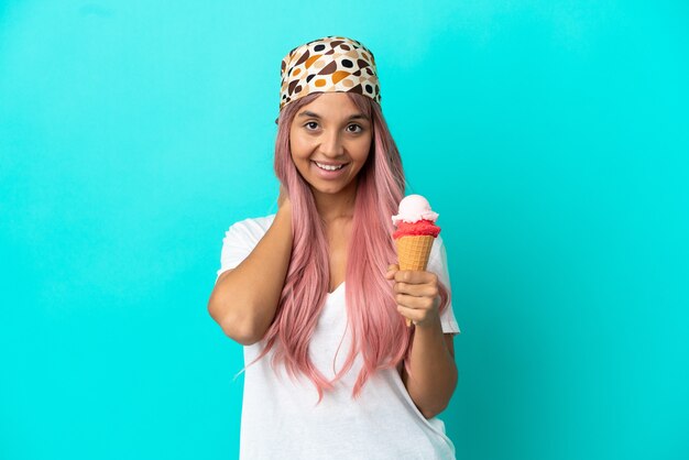 Jeune femme de race mixte avec une glace cornet isolé sur fond bleu en riant