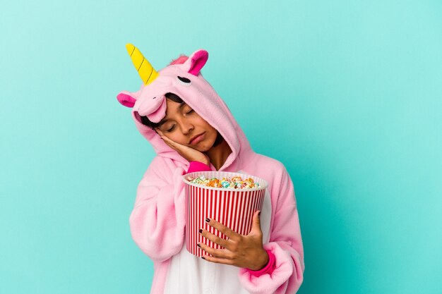 Jeune femme de race mixte portant un pyjama de licorne mangeant du maïs soufflé