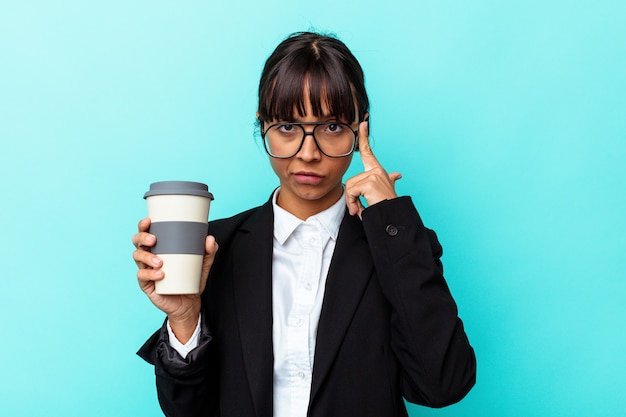 Jeune femme de race mixte tenant un café isolé sur fond bleu pointant le temple avec le doigt, pensant, concentré sur une tâche.