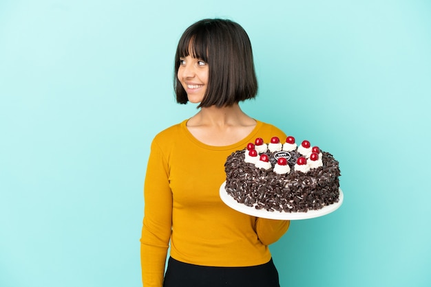 Jeune femme de race mixte tenant un gâteau d'anniversaire à côté