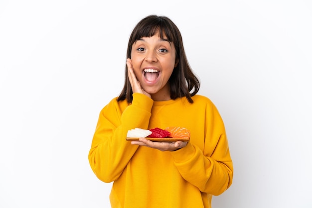 Jeune femme de race mixte tenant un sashimi isolé sur fond blanc avec une expression faciale surprise et choquée