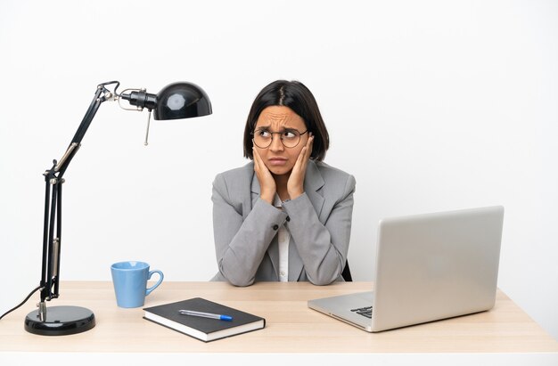 Jeune Femme De Race Mixte Travaillant Au Bureau Frustrée Et Couvrant Les Oreilles