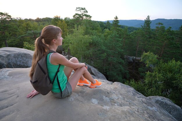 Jeune femme randonneur assis seul sur une montagne rocheuse profitant de la vue sur la nature du soir sur le sentier sauvage Mode de vie actif concept