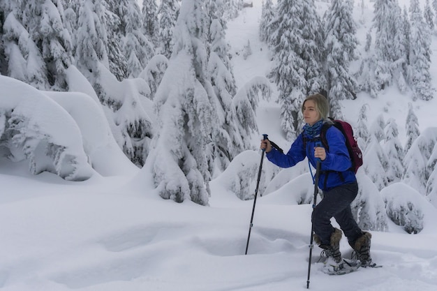 Jeune femme en raquettes dans la neige fraîche