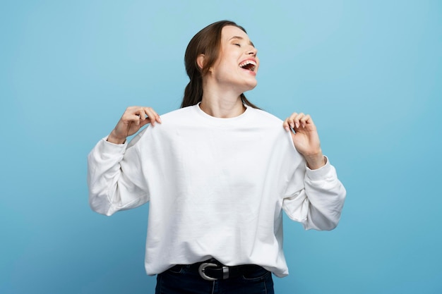 Jeune femme ravie portant une chemise blanche dansant et s'amusant