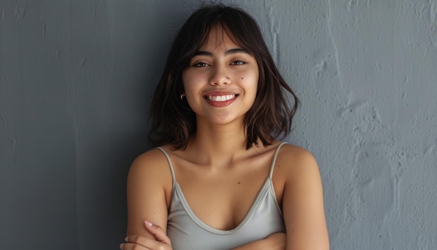 Une jeune femme rayonnante souriant sur un fond gris.