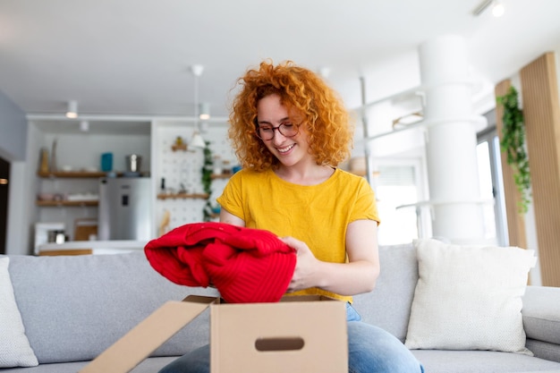 Jeune femme recevant un colis à la maison Achats de vacances en ligne et déballage d'une boîte en carton Service de livraison pendant la quarantaine covid Bonne fille recevant un cadeau Moment de style de vie