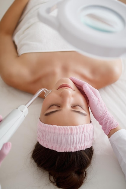 Jeune femme recevant un massage électrique de procédure darsonval au salon de beauté Cosmétologie matérielle