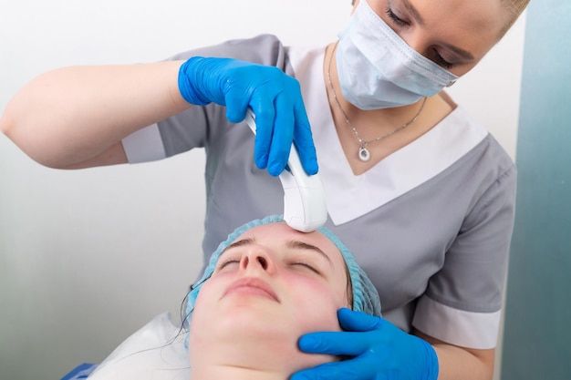 Jeune femme recevant un massage galvanique électrique du visage anti-âge au salon de beauté