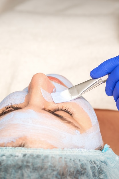 Jeune femme recevant la procédure d'application d'un masque facial au salon spa