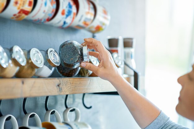 Jeune femme à la recherche d'épices dans la cuisine