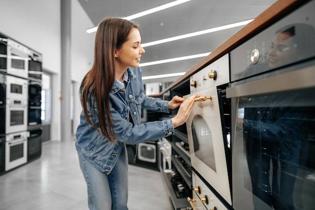 Jeune femme à la recherche d'un nouveau four électrique dans un centre commercial