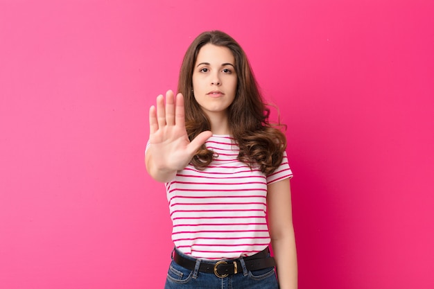 jeune femme à la recherche de sérieux, sévère, mécontent et en colère montrant la paume ouverte faisant un geste d'arrêt