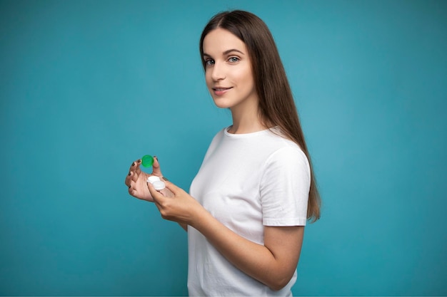 Jeune femme avec récipient de lentilles de contact sur fond bleu