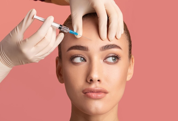 Une jeune femme reçoit une injection de beauté de Botox dans le front.
