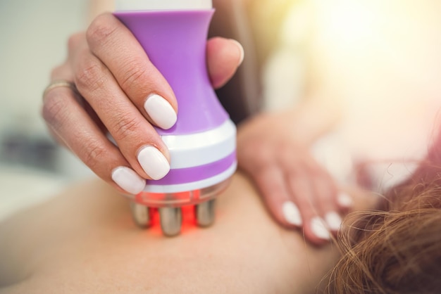 Photo une jeune femme reçoit un massage anticellulite sur le dos avec un dispositif d'aspiration matériel dans le spa