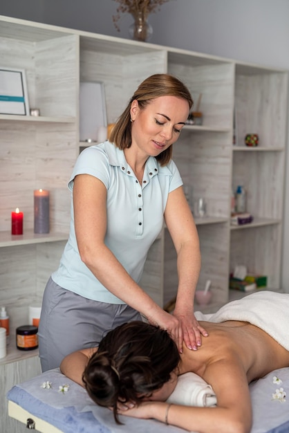 Une jeune femme reçoit un massage relaxant manuel sur le cou allongé sur une table dans un salon de spa