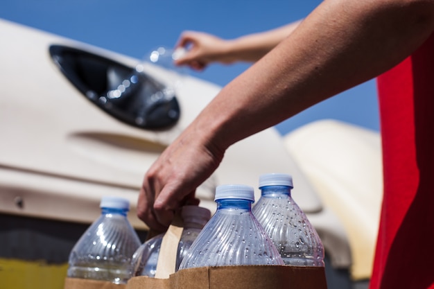 Jeune femme recyclant des bouteilles en plastique