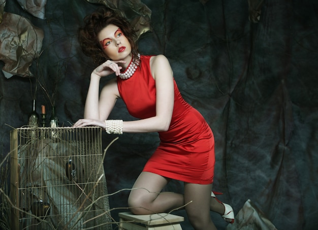 Jeune femme redhair avec visage créatif portant une robe rouge
