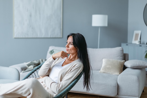 Jeune femme réfléchie assise dans le salon