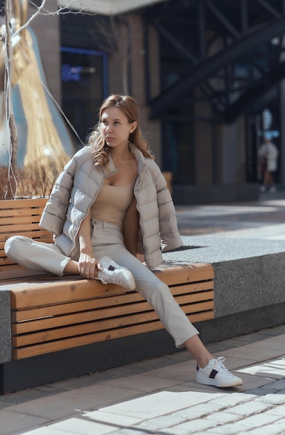 Jeune femme réfléchie et pensive assise seule sur un banc en bois