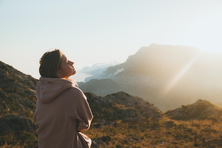 Photo une jeune femme réfléchie sur le sommet d'une montagne contre le ciel