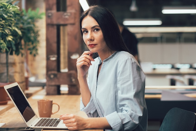 Jeune femme à la réflexion alors qu'il était assis devant un ordinateur portable