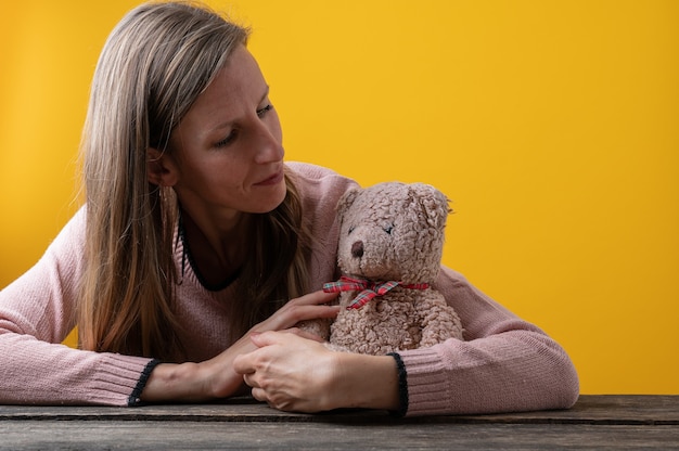 Jeune femme regardant avec amour un ours en peluche le serrant