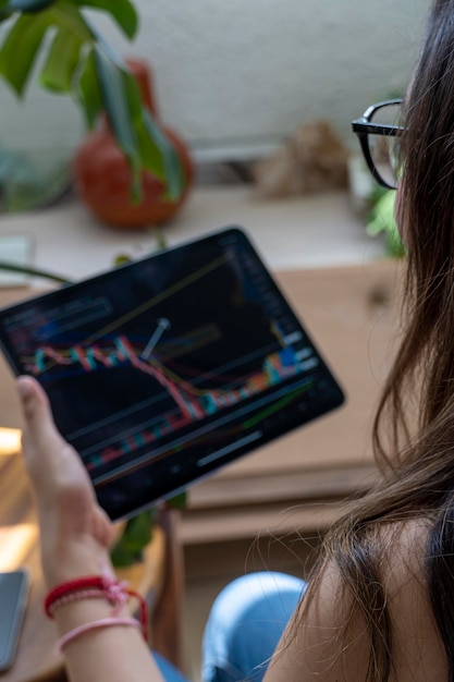 Jeune femme regardant la bourse la nuit le même marché est vu dans le reflet de son verre