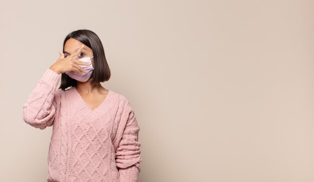 Jeune femme regardant choqué, effrayé ou terrifié, couvrant le visage avec la main et furtivement entre les doigts