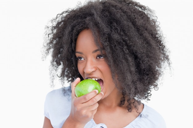 Jeune femme regardant sur le côté tout en mangeant une pomme verte
