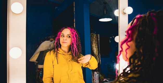 Jeune femme regardant dans le miroir compte tenu de sa nouvelle coiffure Belle femme avec des dreadlocks se lissant devant le miroir