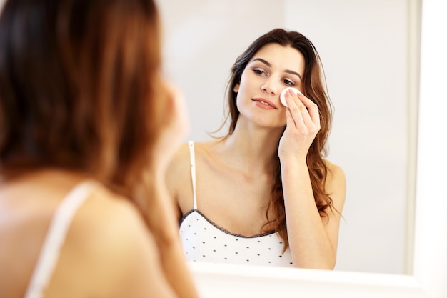 Jeune femme regardant dans le miroir de la salle de bain