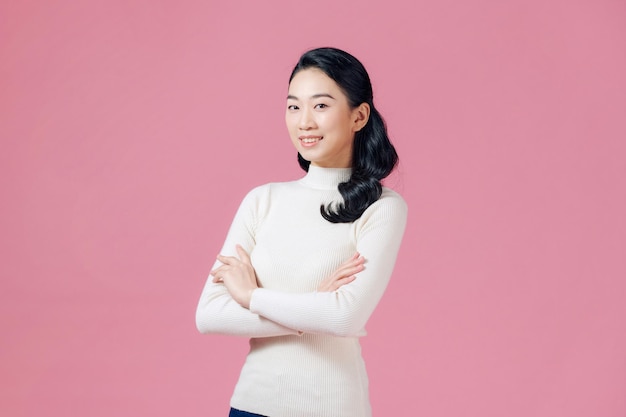 Jeune femme regardant l'espace vide les bras croisés souriant isolé sur fond de couleur rose