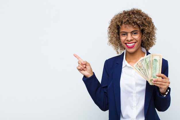 Jeune femme regardant excité et surpris pointant vers le côté et vers le haut pour copier l'espace avec des billets en euros