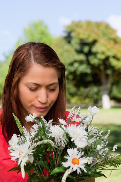 Jeune femme regardant une fleur en se tenant debout dans un parc