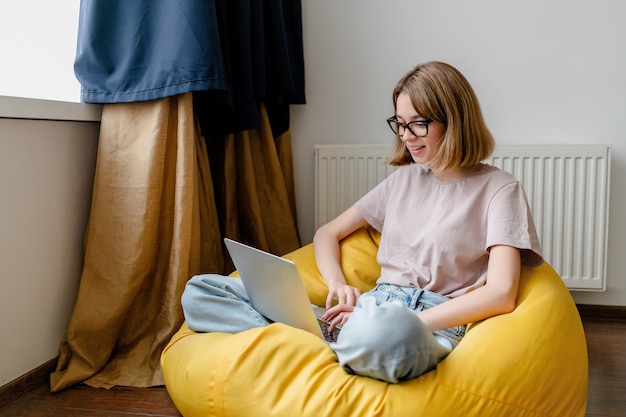 Jeune femme regardant un ordinateur portable travaillant en ligne