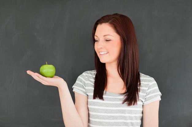 Jeune femme regardant la pomme sur sa paume