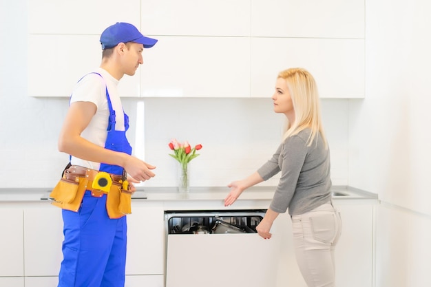 Jeune Femme Regardant Un Technicien Mâle Vérifiant Le Lave-vaisselle Dans La Cuisine.