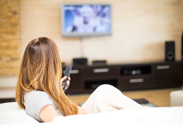 Jeune femme regardant la télévision dans la chambre