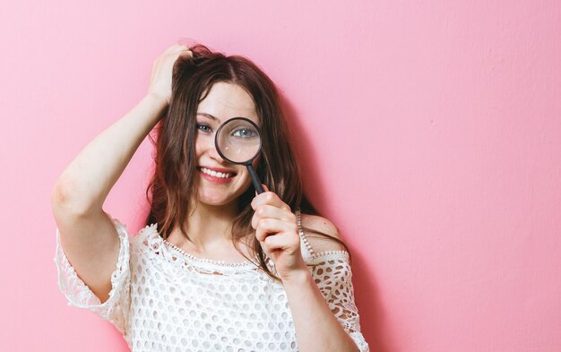 Jeune femme regardant à travers une loupe