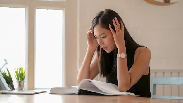 Une jeune femme regardant vers le bas tout en étant assise sur la table