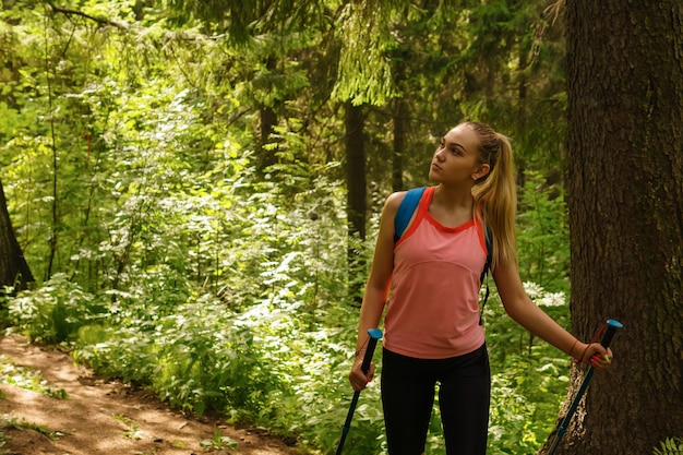 Une jeune femme regarde autour d'elle lors d'une randonnée sur un sentier dans une forêt de montagne