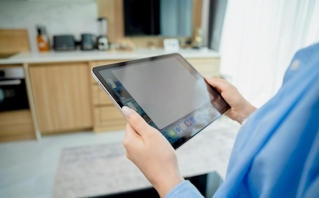 Une jeune femme regarde les caméras de sécurité de la maison sur une tablette.