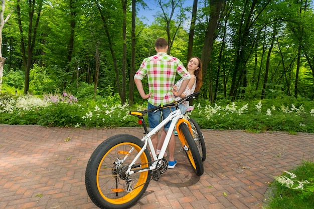 Jeune femme regarde d'un gars en chemise à carreaux vert et rouge et regarde dans la caméra après avoir fait du vélo dans un parc