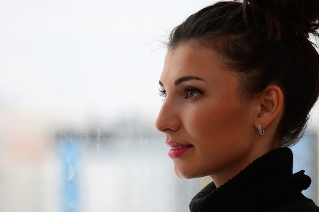 Une jeune femme regarde par la fenêtre d'un nouvel appartement